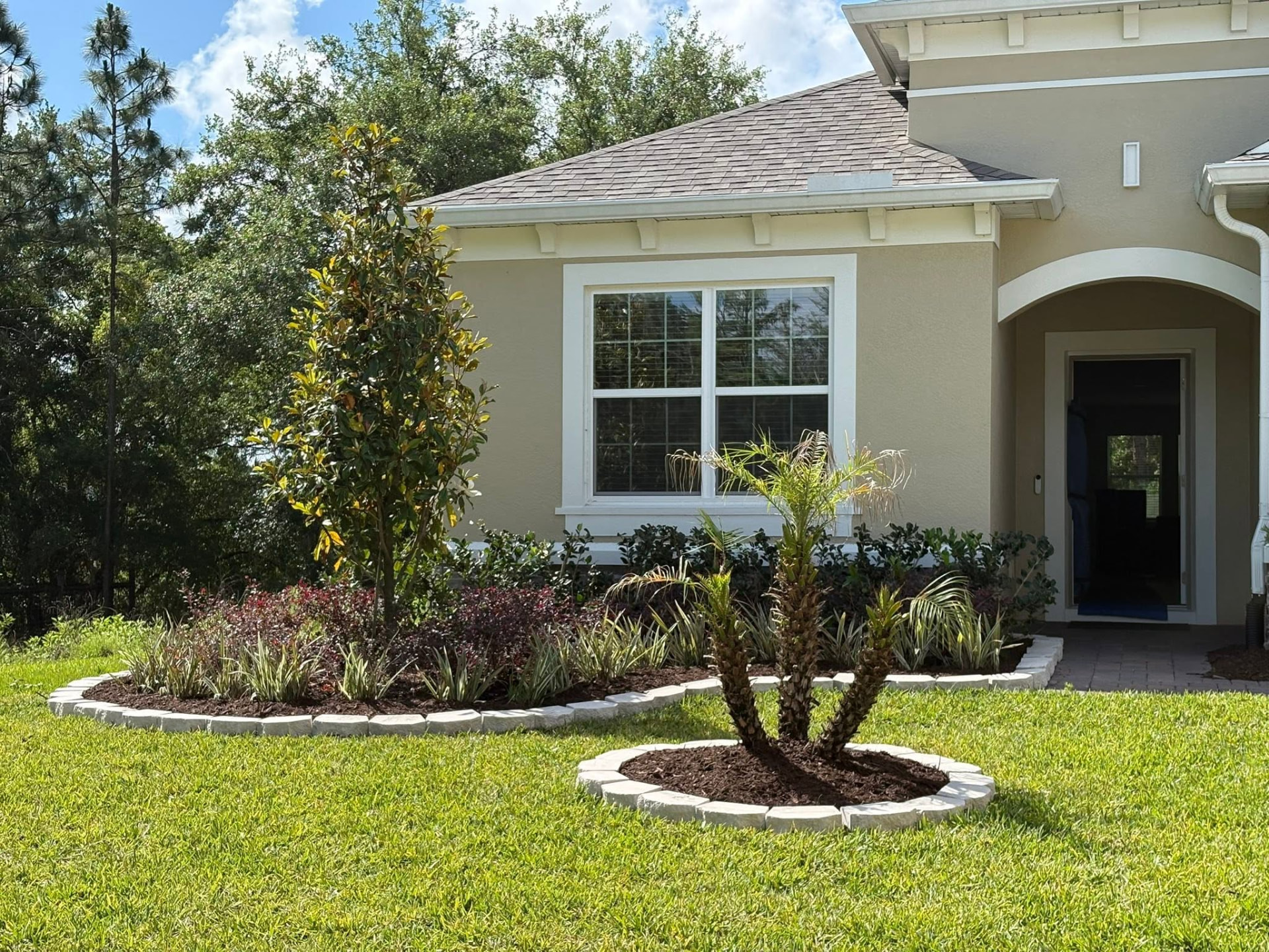 Custom landscape design with palm tree, tropical plants and white stone border